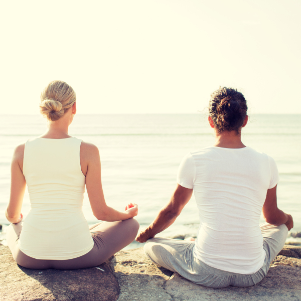 young couple meditating near water